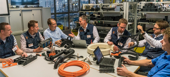 イグスの従業員が製品の載ったテーブルの周りに座る